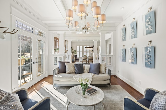 living room featuring wood finished floors, baseboards, french doors, crown molding, and a notable chandelier