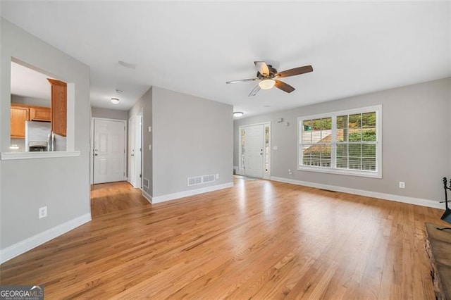 unfurnished living room featuring visible vents, light wood-style flooring, a ceiling fan, and baseboards