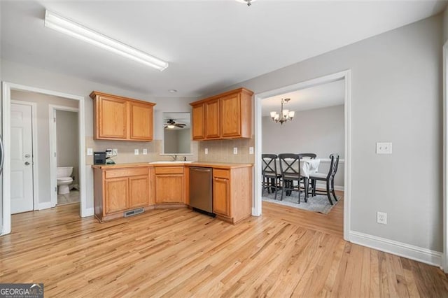 kitchen featuring light wood-type flooring, a notable chandelier, a sink, stainless steel dishwasher, and light countertops