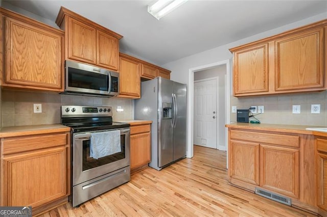 kitchen with light countertops, light wood-style floors, visible vents, and appliances with stainless steel finishes