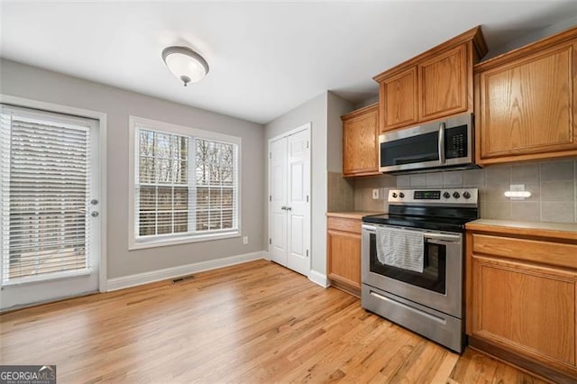 kitchen featuring light wood finished floors, visible vents, backsplash, and stainless steel appliances