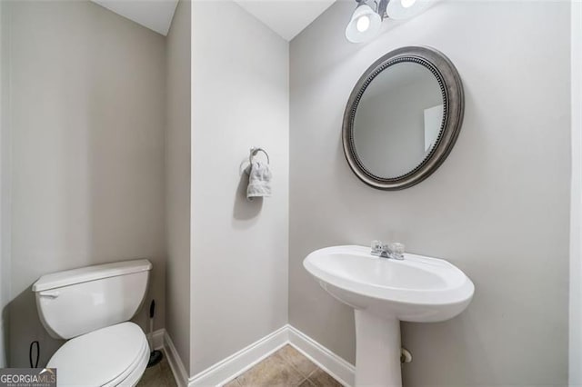 bathroom featuring baseboards, toilet, and tile patterned flooring