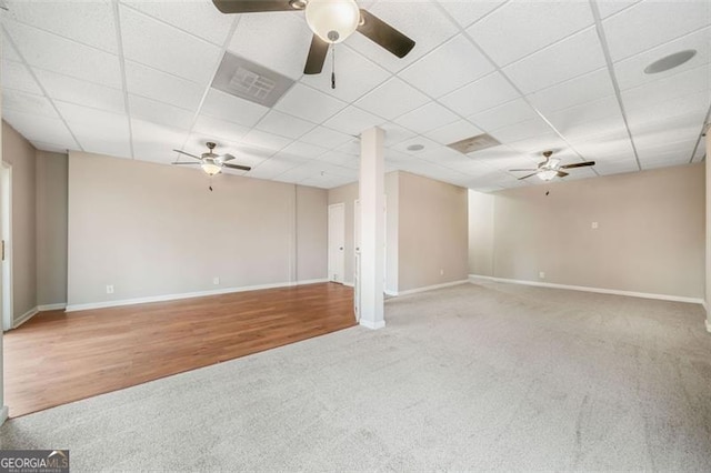 empty room with a drop ceiling, visible vents, carpet floors, and baseboards