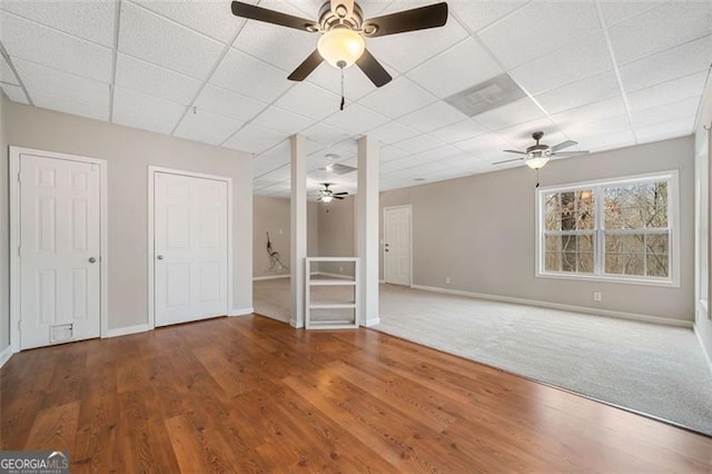 unfurnished room with wood finished floors, a paneled ceiling, and baseboards