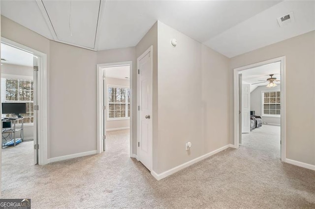 corridor featuring attic access, baseboards, visible vents, and carpet floors