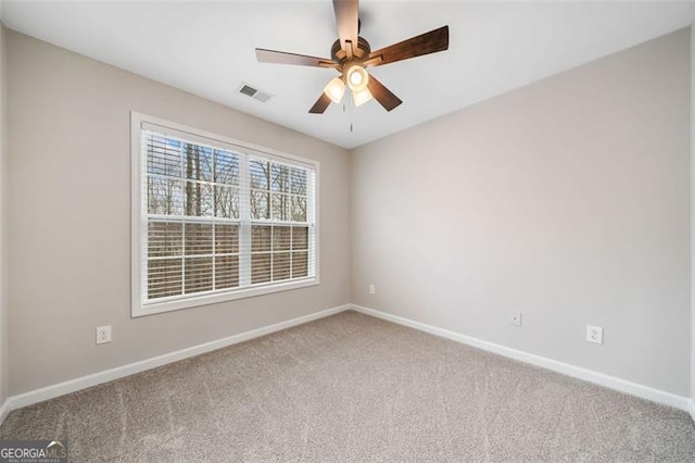 carpeted spare room with visible vents, baseboards, and ceiling fan