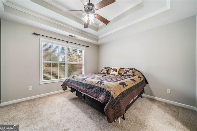 bedroom featuring a ceiling fan, baseboards, carpet floors, a tray ceiling, and crown molding