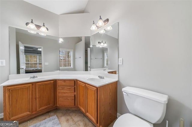 full bath with tile patterned floors, double vanity, toilet, and a sink