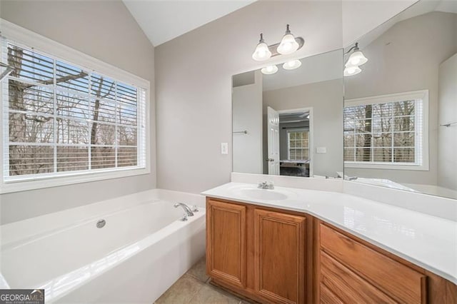 bathroom featuring vanity, a garden tub, vaulted ceiling, and tile patterned flooring