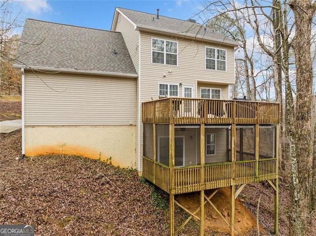 rear view of property featuring a wooden deck, roof with shingles, and a sunroom