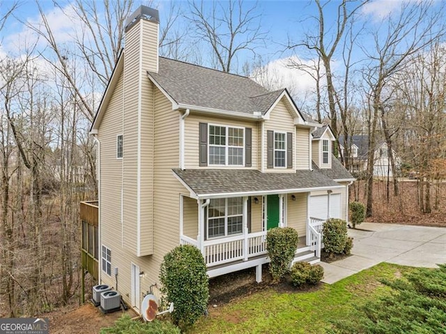 traditional home with a porch, a chimney, driveway, and a shingled roof