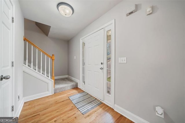 foyer featuring stairs, wood finished floors, and baseboards