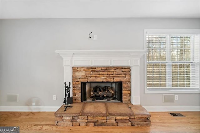 interior details with wood finished floors, visible vents, baseboards, and a fireplace with raised hearth