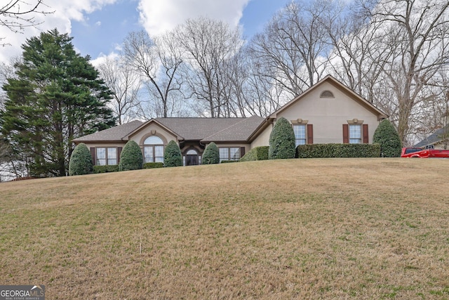 view of front of property with stucco siding, a shingled roof, and a front lawn