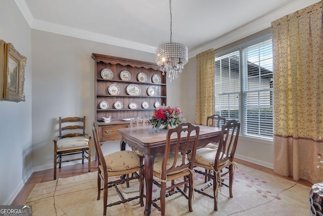 dining area with an inviting chandelier, crown molding, baseboards, and light wood finished floors