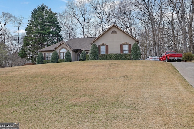 view of front of home with a front yard, driveway, and stucco siding