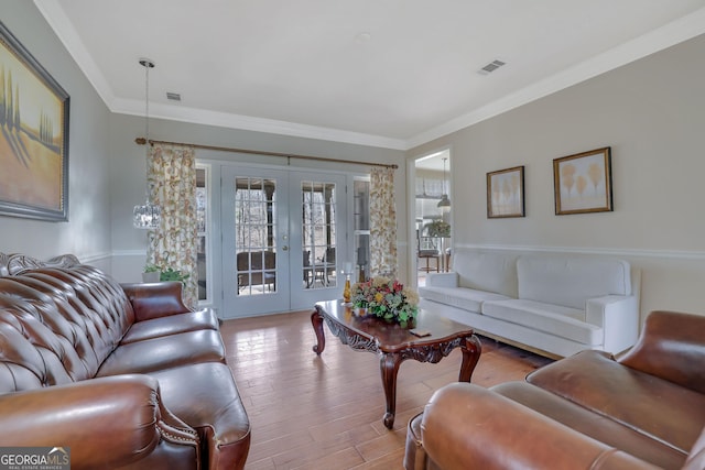 living area featuring visible vents, wood-type flooring, ornamental molding, and french doors