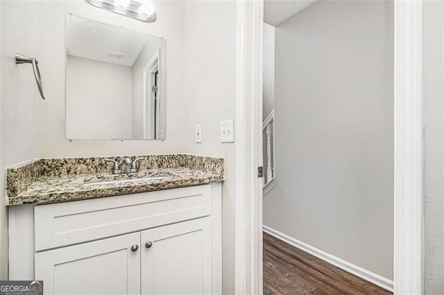 bathroom with vanity, baseboards, and wood finished floors