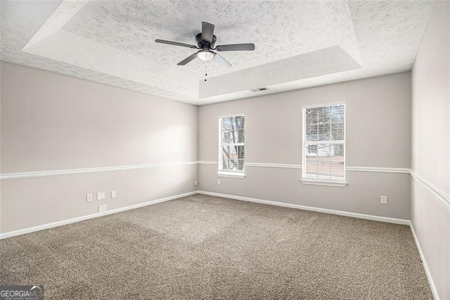 carpeted spare room featuring baseboards, a raised ceiling, a textured ceiling, and ceiling fan