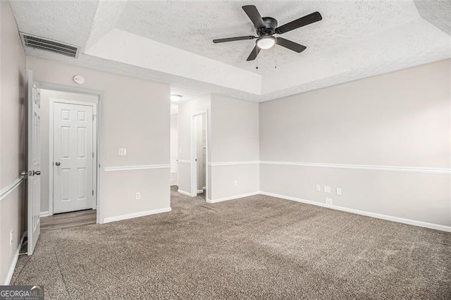 empty room with visible vents, a textured ceiling, and a tray ceiling