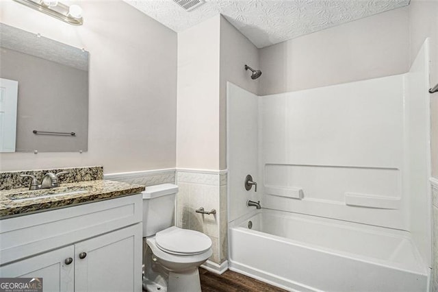 bathroom featuring toilet, a wainscoted wall, and a textured ceiling