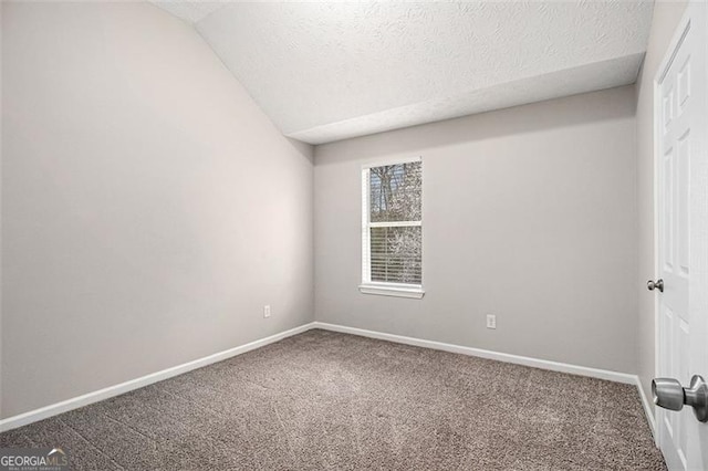 carpeted empty room featuring baseboards, a textured ceiling, and lofted ceiling