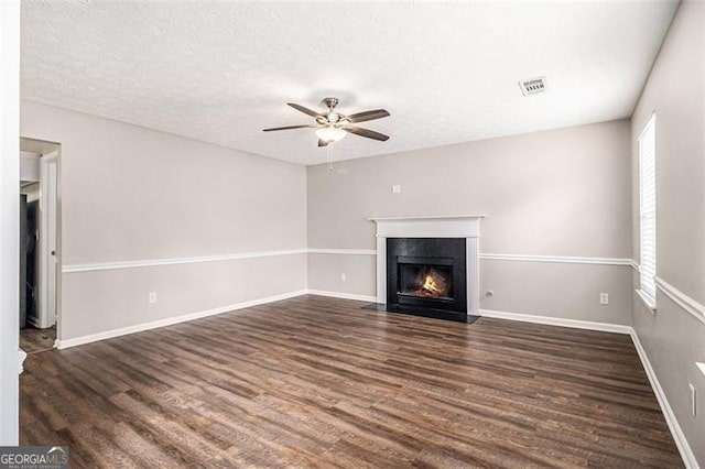 unfurnished living room with visible vents, baseboards, a fireplace, dark wood-style flooring, and a textured ceiling