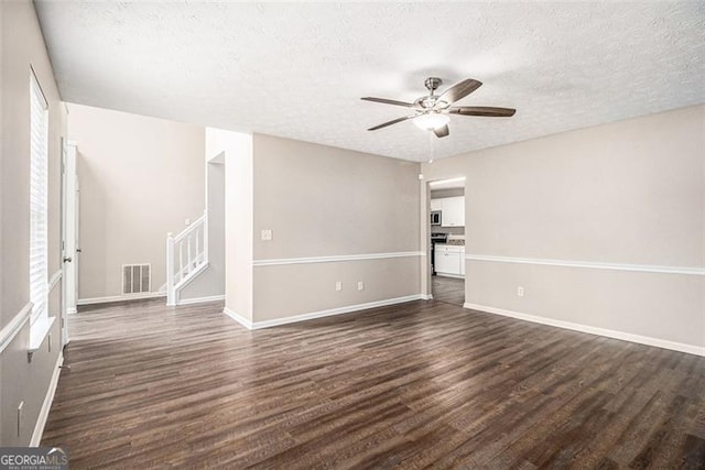 spare room featuring dark wood finished floors, visible vents, a textured ceiling, and stairs