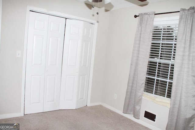 unfurnished bedroom featuring carpet flooring, baseboards, a closet, and ceiling fan