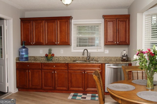 kitchen featuring light wood-style flooring, a sink, light stone counters, stainless steel dishwasher, and a textured ceiling