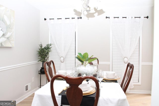 dining space with an inviting chandelier, light wood-style floors, visible vents, and baseboards