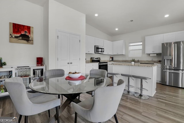 dining room with recessed lighting, light wood-type flooring, visible vents, and vaulted ceiling