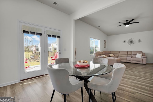 dining space with visible vents, baseboards, lofted ceiling, wood finished floors, and a ceiling fan