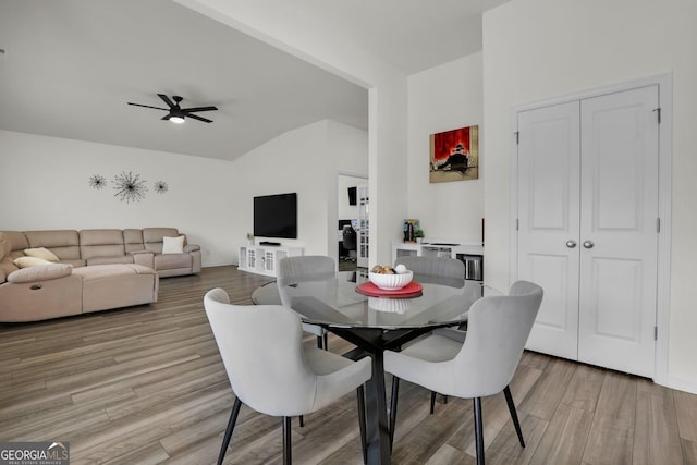 dining room with light wood-style flooring, baseboards, ceiling fan, and vaulted ceiling