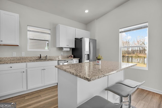 kitchen featuring a breakfast bar area, stainless steel appliances, light wood-style floors, and a sink