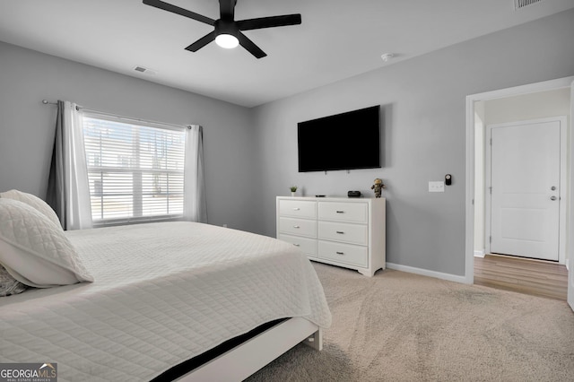 bedroom with visible vents, light colored carpet, a ceiling fan, and baseboards