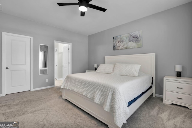 bedroom with a ceiling fan, light colored carpet, baseboards, and connected bathroom