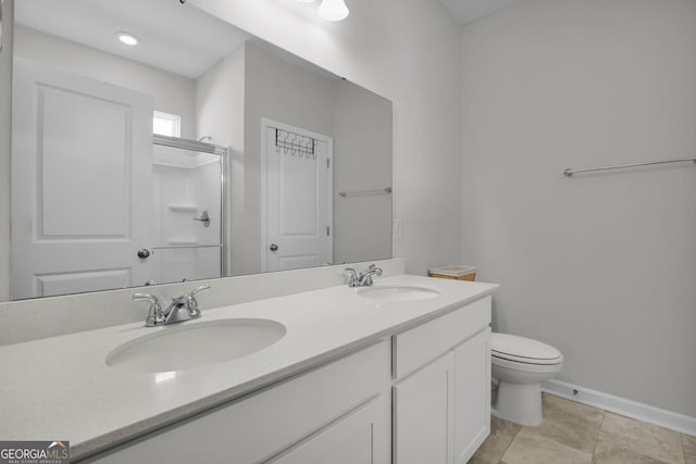 bathroom featuring double vanity, a shower with door, toilet, and a sink