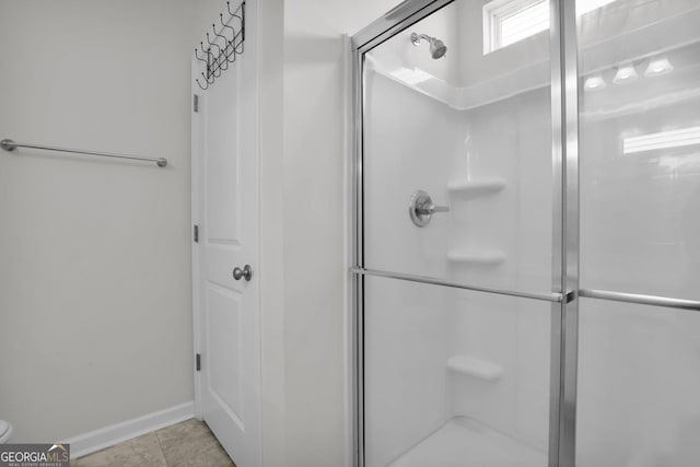 bathroom featuring tile patterned floors, baseboards, toilet, and a shower stall