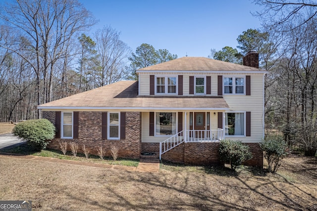 view of front of property with brick siding, covered porch, and a chimney