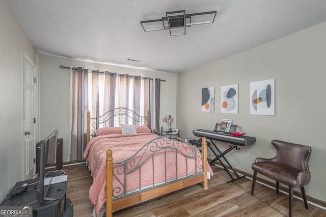 bedroom featuring visible vents, baseboards, and wood finished floors