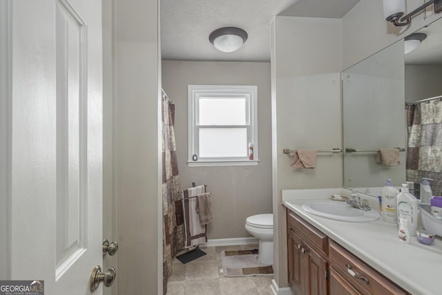 full bath featuring toilet, a textured ceiling, vanity, and baseboards