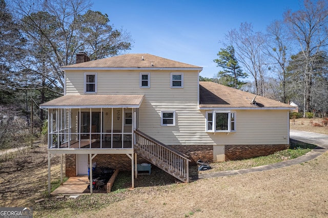 rear view of house with stairway, a chimney, and a sunroom