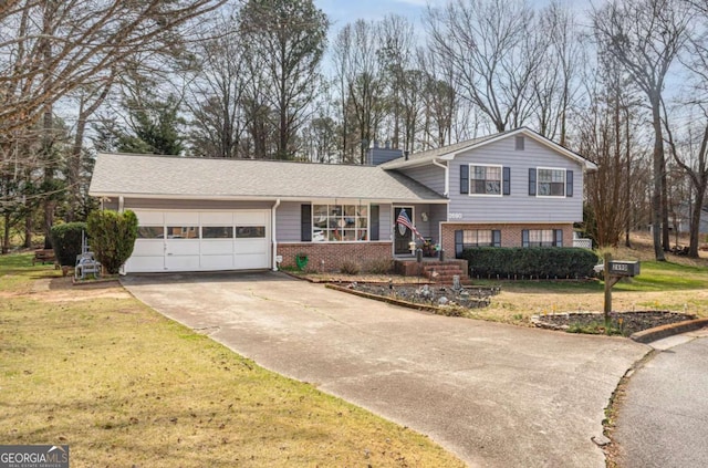 split level home with a front yard, driveway, a shingled roof, a garage, and brick siding