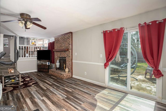 living area featuring a brick fireplace, wood finished floors, baseboards, and ceiling fan