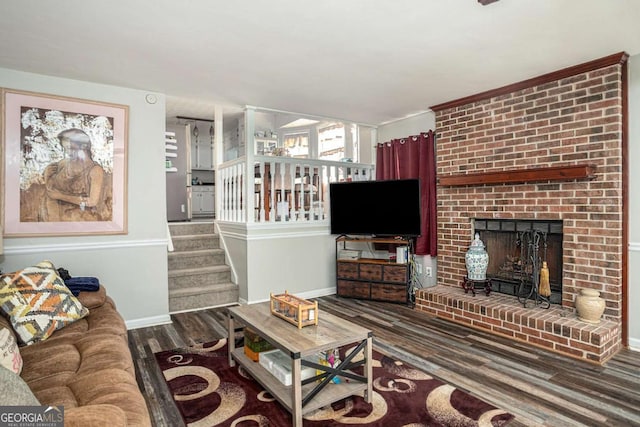 living area with stairway, a brick fireplace, baseboards, and wood finished floors