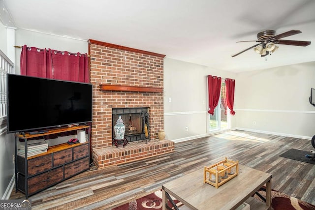 living area featuring a fireplace, wood finished floors, baseboards, and a ceiling fan