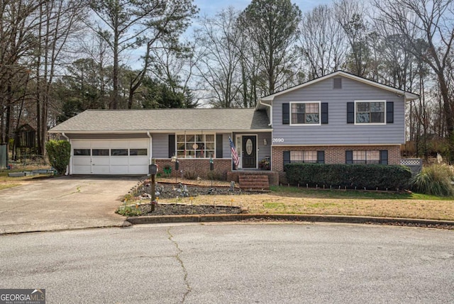 split level home with a front yard, a garage, brick siding, and driveway