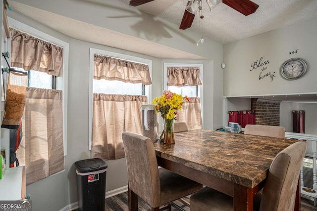 dining space with ceiling fan, a textured ceiling, baseboards, and vaulted ceiling