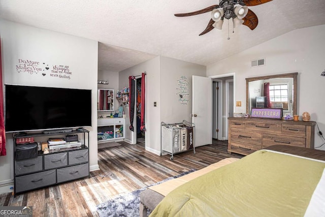 bedroom with wood finished floors, baseboards, visible vents, vaulted ceiling, and a textured ceiling